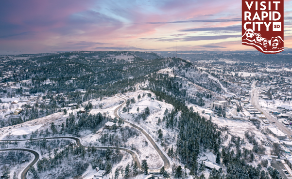 Sun sets in pink swirls above the snow-dusted landscape overlooking Downtown Rapid City